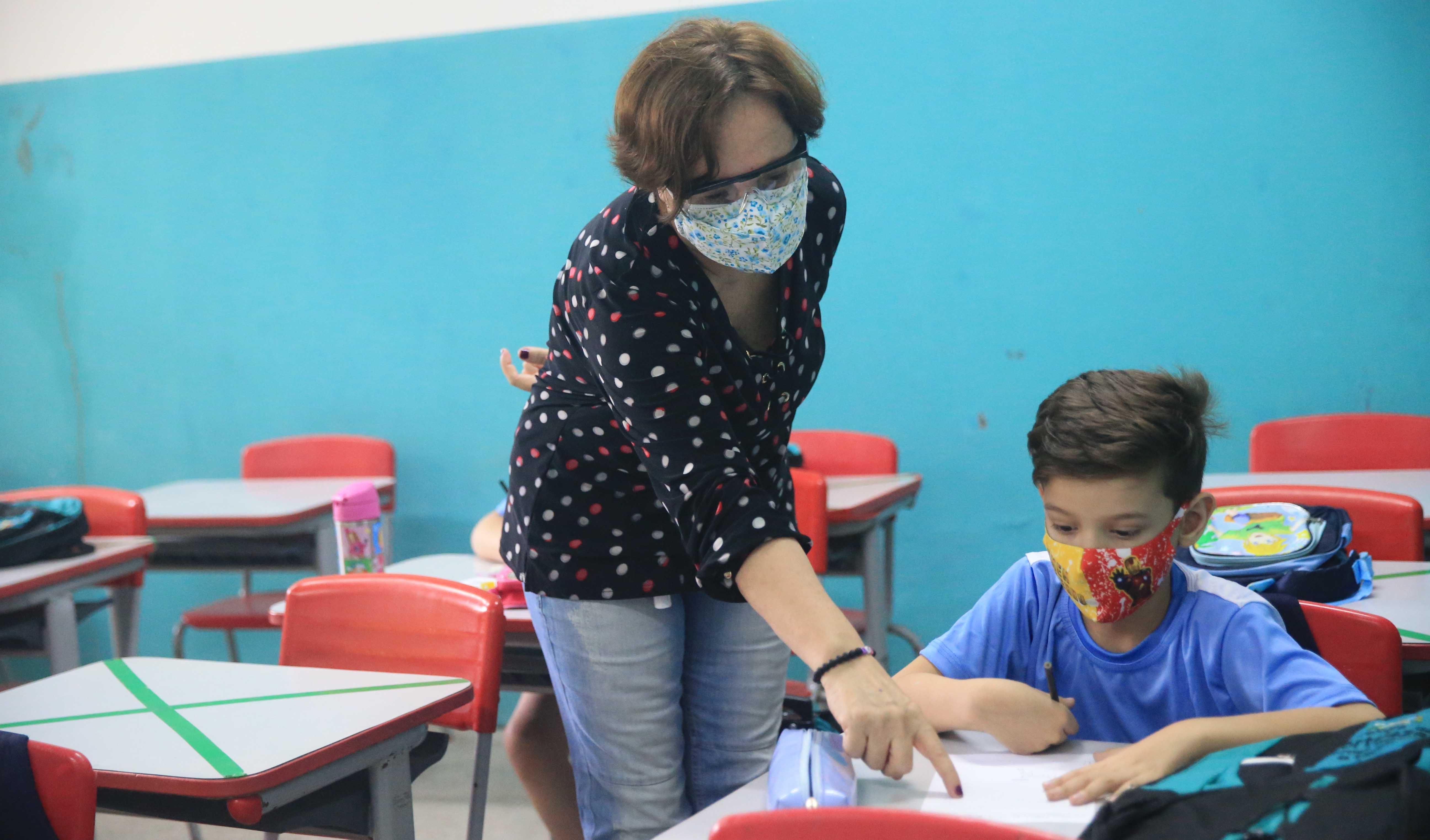 professora orientando aluno em sala de aula